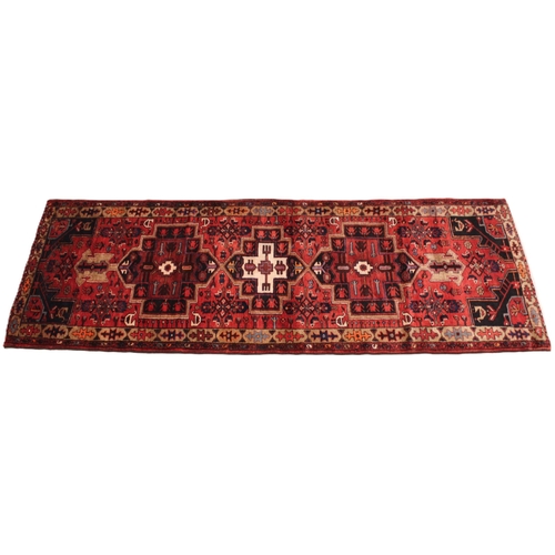 729 - A rich red ground Persian Heriz runner, bespoke medallion design, the three linked geometric medalli... 