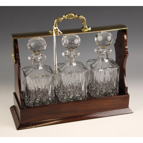 740 - A mahogany finish three bottle tantalus, late 20th century, fitted with three matching square decant... 