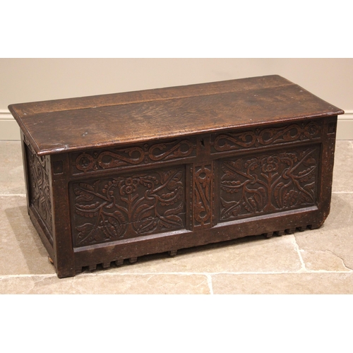 776 - A late 17th century carved oak coffer, the hinged and moulded top over a carved frieze and twin pane... 