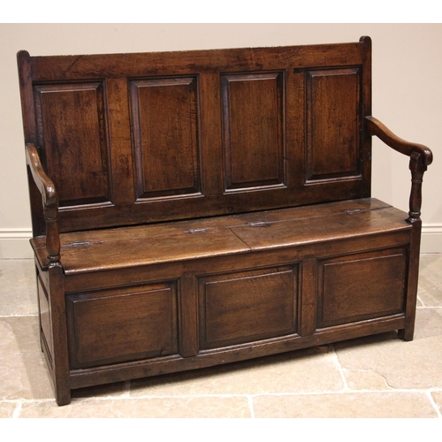 784 - An 18th century Welsh oak box settle, of cottage proportions, the four panel back extending to the d... 