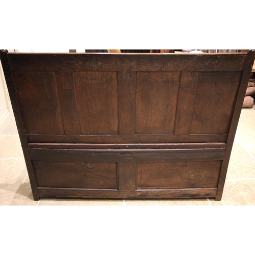 784 - An 18th century Welsh oak box settle, of cottage proportions, the four panel back extending to the d... 