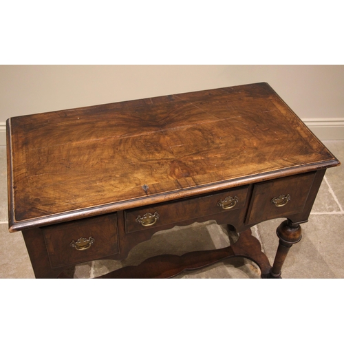 789 - A William and Mary style figured walnut low boy, 19th century, the book veneered moulded top over an... 