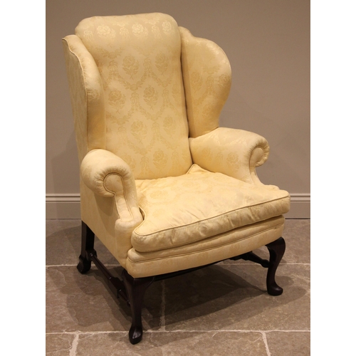 807 - A George II style mahogany wingback armchair, late 20th century, in yellow damask foliate fabric, th... 