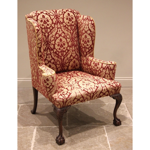 808 - A George III style wing back armchair, mid 20th century, of country house proportions, in embossed f... 