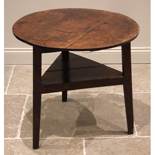 816 - A 19th century oak cricket table, the circular plank top upon three chamfered supports, united by a ... 