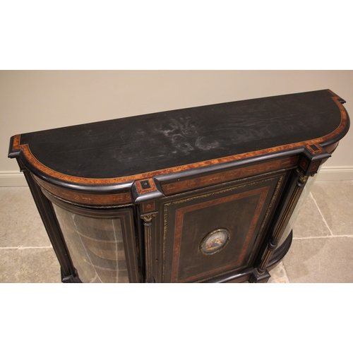 835 - A Victorian ebonised and amboyna banded credenza, of bowfront form, the central cupboard door applie... 