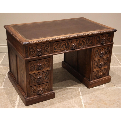 878 - A carved oak green man twin pedestal desk, late 19th/early 20th century, the moulded top inset with ... 