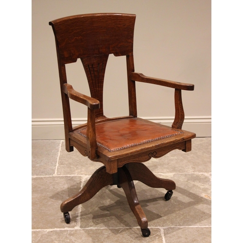 898 - An early 20th century oak desk chair, the shaped back with pierced splat over a padded leather seat ... 