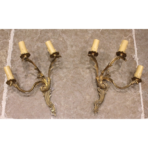 687 - A pair of gilt metal Rococo three branch wall light fittings, of typical cast scroll foliate form, e... 