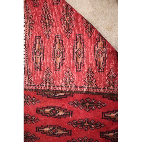 718 - A red ground Turkmen carpet, with all over Bokhara guls, punctuated by rows of lozenge shaped guls, ... 