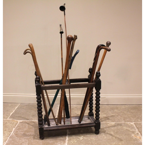 672 - A collection of walking sticks and canes to an early 20th century bobbin turned oak stick stand, to ... 