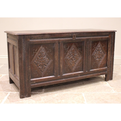 794 - An 18th century oak coffer, the moulded two plank top with carved serrated banding, opening to a fit... 