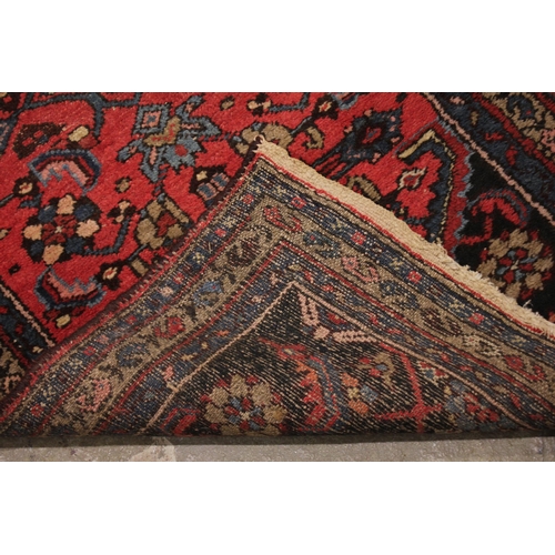 733 - A Caucasian hand knotted wool runner, in red, blue and brown colourways, the central hexagonal blue ... 