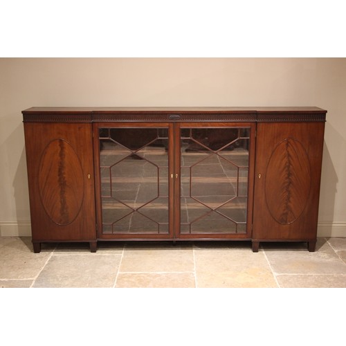 795 - A 19th century inverted breakfront mahogany bookcase, the nulled frieze with a central oval crest ov... 