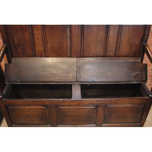 784 - An 18th century Welsh oak box settle, of cottage proportions, the four panel back extending to the d... 