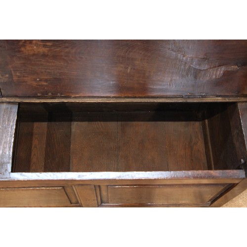 784 - An 18th century Welsh oak box settle, of cottage proportions, the four panel back extending to the d... 