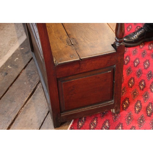 784 - An 18th century Welsh oak box settle, of cottage proportions, the four panel back extending to the d... 