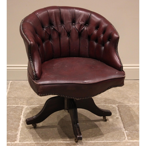 747 - An oxblood red leather revolving desk chair, early 20th century, the button back tub seat applied wi... 