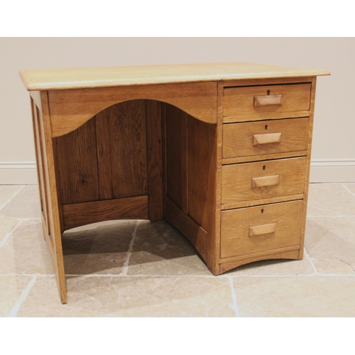 751 - A George V honey oak kneehole desk, with an arched kneehole recess and bank of four graduated drawer... 