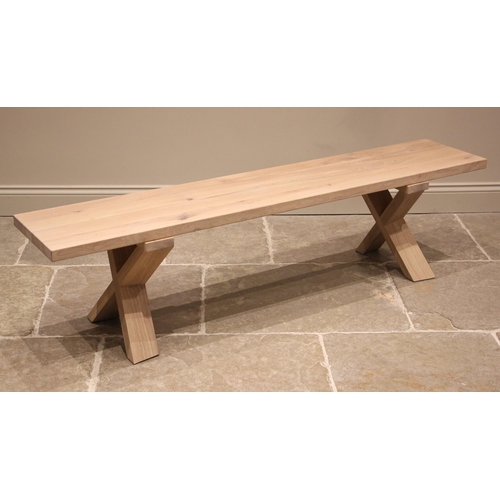 764 - A contemporary Heals 'Oslo' natural oak bench, the slab top upon a pair of 'X' trestle type supports... 