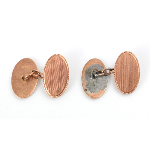 163 - A pair of 9ct yellow gold cufflinks, the oval cufflinks with engine turned detail, 2cm long, stamped... 