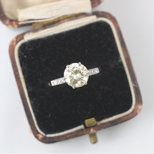 132 - A mid 20th century diamond solitaire ring, the central round cut diamond with a trio of diamonds set... 