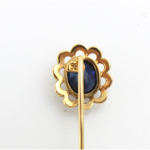 181 - An untested sapphire set stick pin, the cushion cut untested sapphire within an openwork yellow meta... 