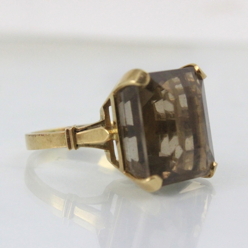 255 - An untested smoky quartz dress ring, the emerald cut stone with yellow metal claw setting edge and p... 