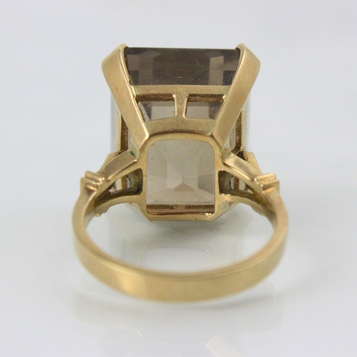 255 - An untested smoky quartz dress ring, the emerald cut stone with yellow metal claw setting edge and p... 