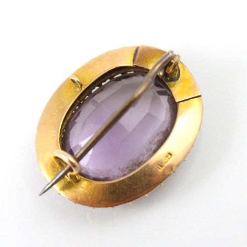 272 - An early 20th century untested amethyst and seed pearl set brooch, the oval cut stone within surroun... 