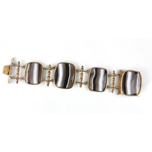 281 - A 19th century style banded agate panel bracelet, the four rounded rectangular panels within gold pl... 