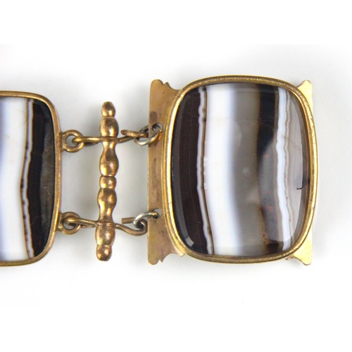 281 - A 19th century style banded agate panel bracelet, the four rounded rectangular panels within gold pl... 