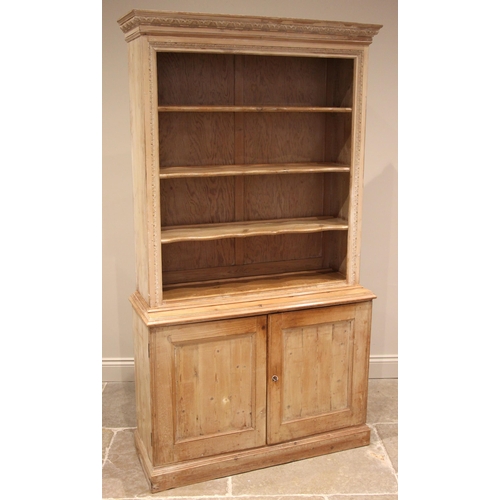 1013 - A 19th century limed pine bookcase, the moulded and carved foliate cornice, over three open wavy sha... 