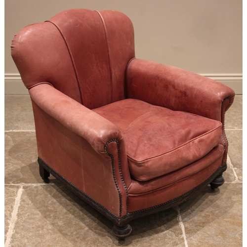 1037 - A 1930's oak and leather armchair, the scalloped back rest extending to padded scrolled arms, applie... 