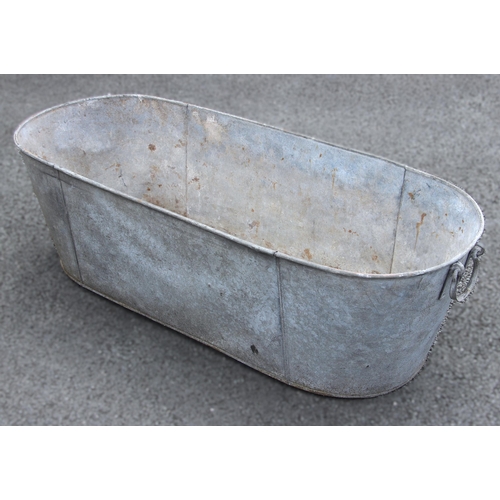 1106 - A galvanized tin metal bath, of typical oval form, applied with swing handles to both ends, 41cm H x... 