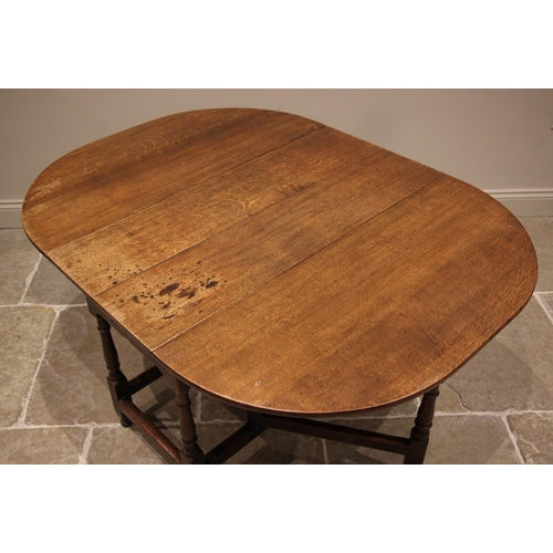 933 - A George III oak drop leaf dining table, the oval top above a single frieze drawer, upon ring turned... 