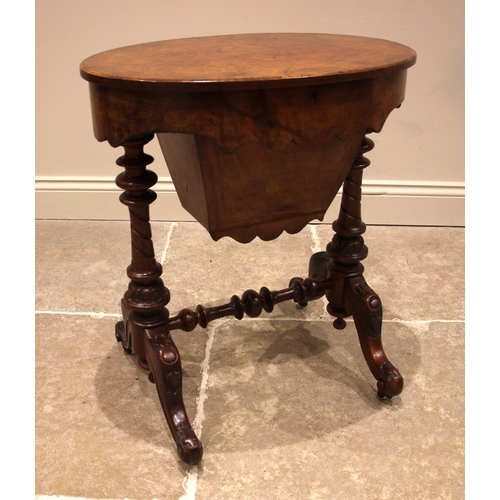 965 - A Victorian figured walnut sewing table, the quarter veneered oval top opening to a compartmented in... 