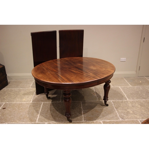 976 - A Victorian mahogany extending dining table, the oval top upon acanthus baluster legs culminating in... 