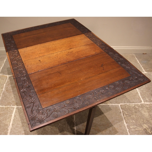 997 - A 19th century carved oak gate leg dining table, the rectangular drop leaf top with a carved trailin... 