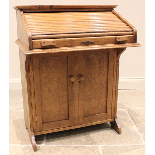 1021 - A medium oak student's roll top desk, circa 1930, the tambour front opening to a compartmented inter... 