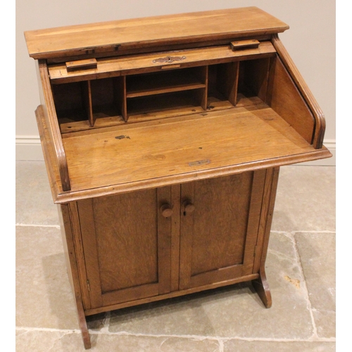 1021 - A medium oak student's roll top desk, circa 1930, the tambour front opening to a compartmented inter... 