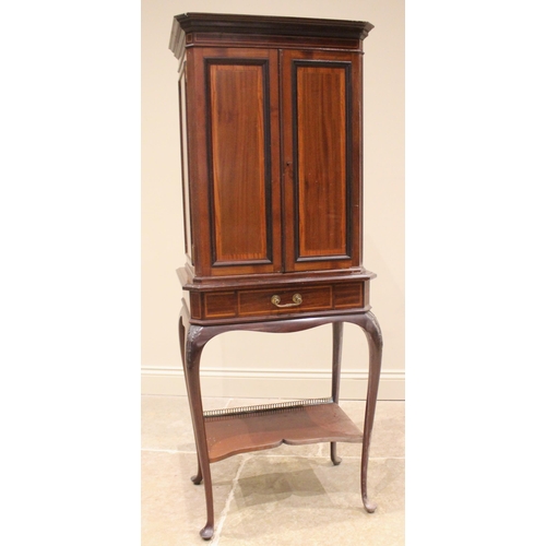 1023 - An Edwardian mahogany and satinwood banded music cabinet on stand, the moulded cornice with canted f... 