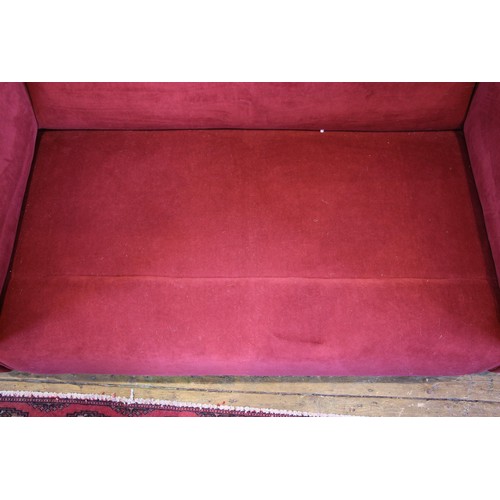 1049 - A contemporary two seater Heals type sofa, in red velour fabric, the out swept arms enclosing a pair... 