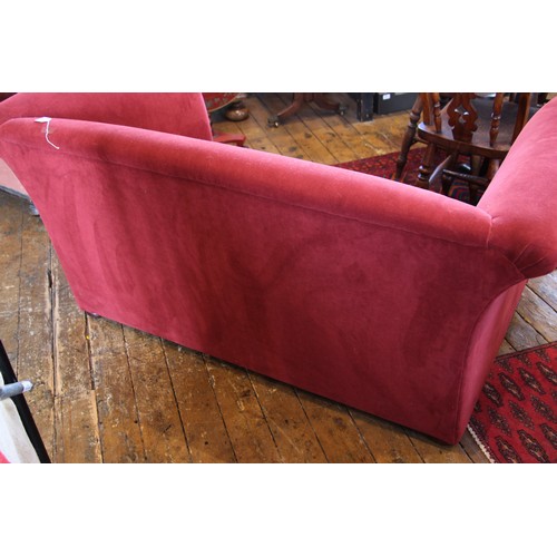 1049 - A contemporary two seater Heals type sofa, in red velour fabric, the out swept arms enclosing a pair... 