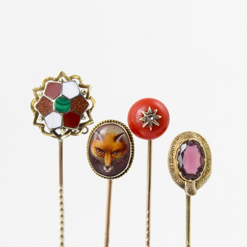 112 - A group of four stick pins, including a 19th century coral and diamond example, the spherical coral ... 