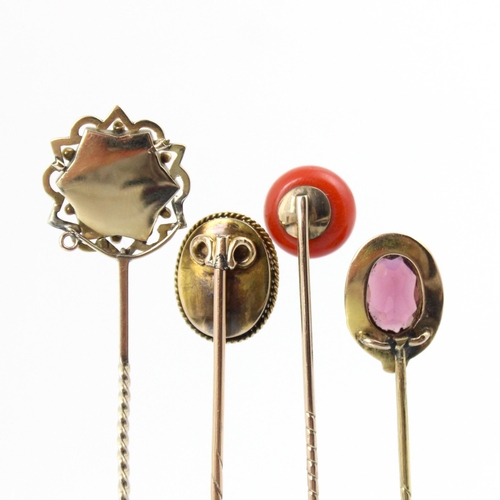 112 - A group of four stick pins, including a 19th century coral and diamond example, the spherical coral ... 