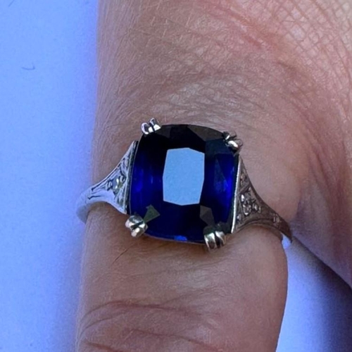 121 - An early 20th century Art Deco sapphire and diamond ring, the central cushion cut sapphire with doub... 