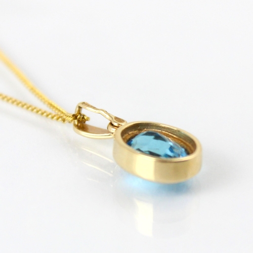 124 - An untested blue topaz pendant, the oval cut blue stone within 9ct yellow gold rub over mount, stamp... 