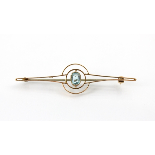 129 - A 20th century untested aquamarine set bar brooch, the cushion cut blue stone within milgrain yellow... 