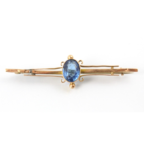 129 - A 20th century untested aquamarine set bar brooch, the cushion cut blue stone within milgrain yellow... 